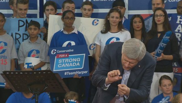 "He'll run, he says, a modest deficit, a tiny deficit – so small you can hardly see the deficit," a sarcastic Harper said as he made the gesture. (Image: globalnews.ca)